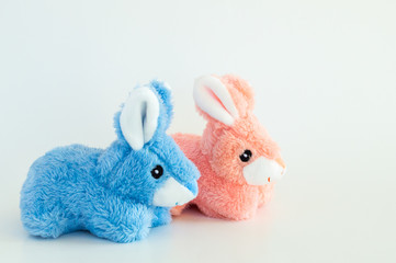 pink and blue toy Easter bunnies facing right isolated on a solid background
