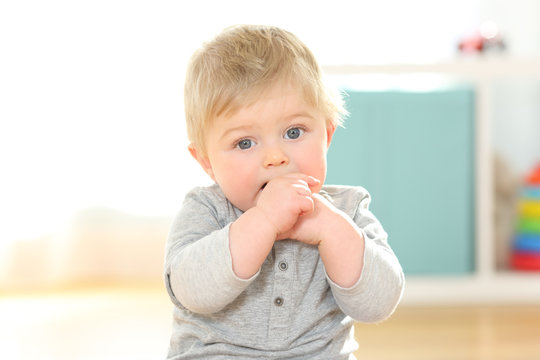 Portrait of a kid biting his fingers looking at you