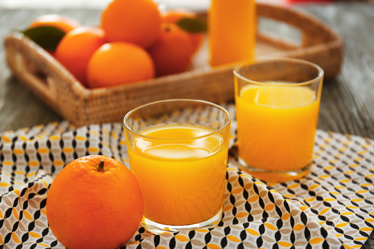 Glasses with fresh orange juice and fruit on table