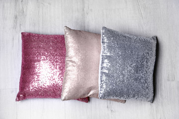 Shiny decorative pillows on wooden floor