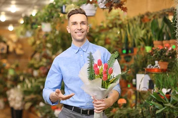 Photo sur Plexiglas Fleuriste Portrait of young man with flowers in greenhouse. Small business owner