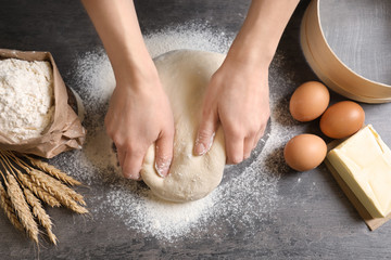 Woman kneading dough on table, closeup