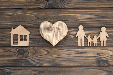 family figures, heart, house against the background of a wooden table. property insurance.