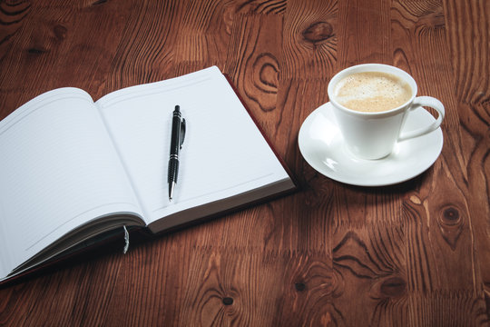 a Cup of cappuccino and open an empty notebook on a wooden table. The concept of breakthrough in the work. Relax