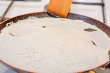 Pancakes are fried in a frying pan. Fried pancakes. Cooking pancakes. Russian folk dish. Maslenitsa.