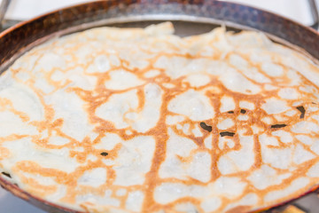 Pancakes are fried in a frying pan. Fried pancakes. Cooking pancakes. Russian folk dish. Maslenitsa.