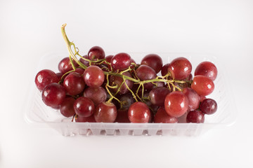 red grapes in plastic container isolated on white background