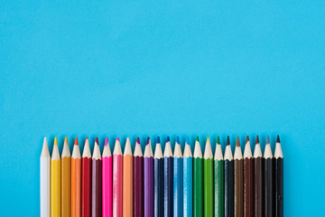 multicolored colored pencils isolated on blue background with copy space