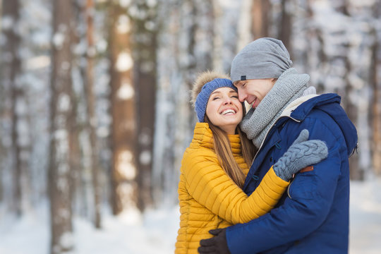 Portrait of happy young couple in a bright clothes in a winter forest
