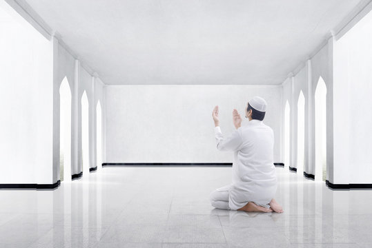 Back View Of Asian Muslim Man Kneeling And Praying To God