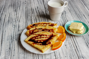 Pancakes on a white plate with honey and a cup of milk. Delicious breakfast.