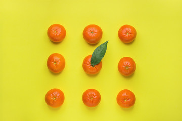 Bright Ripe Tangerines Arranged in Rows in Square One with Green Leaf in Middle. Yellow Background. Food Knolling. Styled Creative Image. Tropical Fruit Vacation Summer Vegan Concept