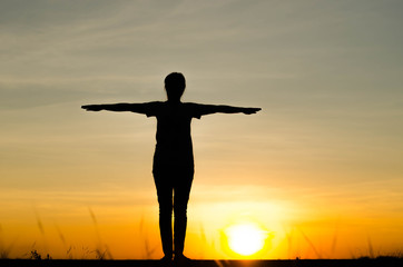 Woman silhouette is standing, raise one's hand for exercise, on evening .