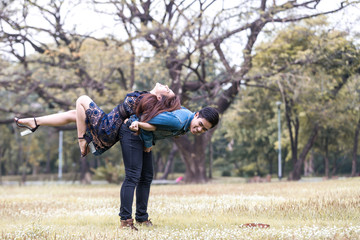 Asian couple lovers under a vast field of nature in a park.