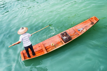 Fototapeta premium Top view of Asian boatman catching trash from river