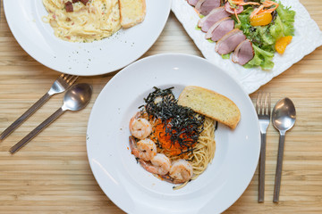 Top view of Japanese style pasta with shrimp, ebiko(red caviar) and seaweed on wood background.