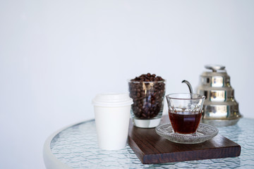 Coffee in a transparent cup on a wooden plank. In the background is a jar of coffee aroma and coffee beans. Close-up with copy space