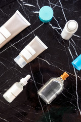 Bottles and tubes with salon cosmetic products from above. Skincare routine, anti-age moisturizers, treatments, serum, body and hair oil. Minimalism beauty blogging concept. Black marble background