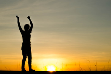 Fototapeta premium Woman silhouette is standing, raise one's hand for exercise, on evening .