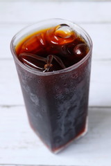 Top view of iced coffee in trasparent glass on white wooden background.