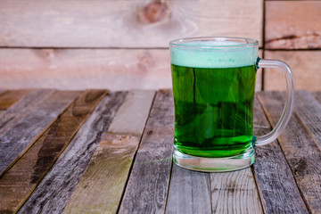 Single mug of green beer on wooden background