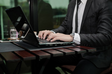 Young Asian businessman working with a laptop in a coffee shop.