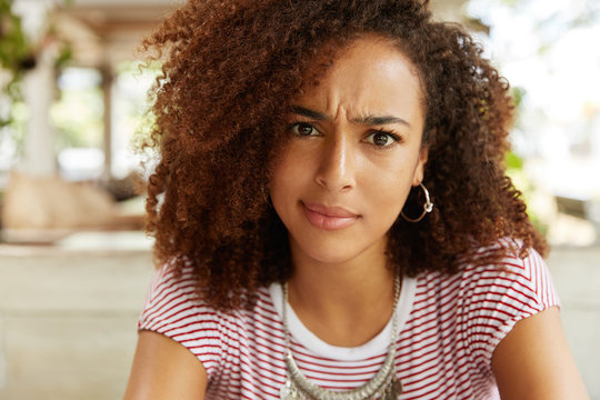 Close up shot of discontent female with pure dark skin, looks with dissatisfied expression as recieves unpleasant news, can`t believe in something. Puzzled African American woman feels embarrassment
