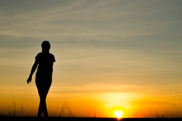 Woman silhouette is standing, raise one's hand for exercise, on evening .