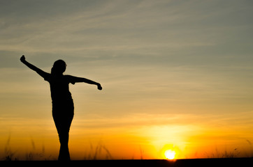 Woman silhouette is standing, raise one's hand for exercise, on evening .