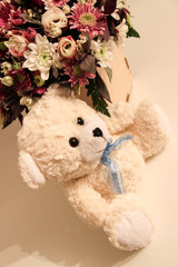 Teddy bear on the background of a spring bouquet of flowers