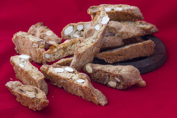 Pieces of Italian cookies from biscotti with almonds chaotically close-up on a red background
