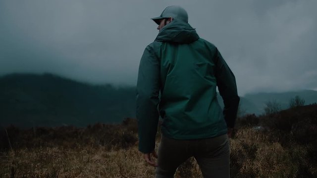 Man Walking in a Dark Misty Mountain Field