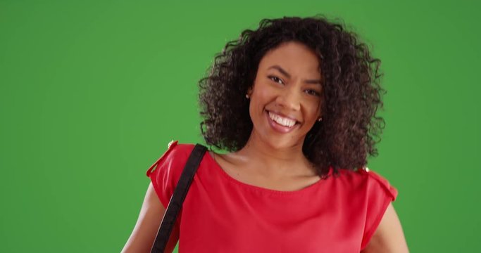 Beautiful Black woman with radiant smile twirling on greenscreen background. Portrait of pretty millennial African American woman laughing and smiling playfully on green screen background. 4k