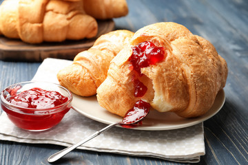 Delicious croissants with jam on table