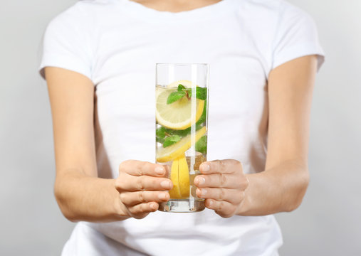 Young woman with glass of lemonade on grey background, closeup