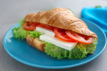 Plate with tasty croissant sandwich on table