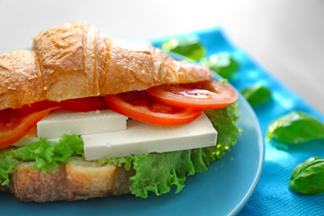 Plate with tasty croissant sandwich on table
