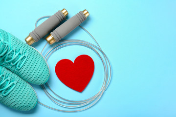 Gym stuff and red heart on color background. Cardio training concept