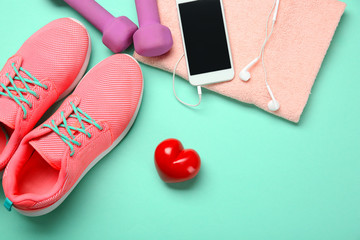 Fototapeta na wymiar Gym stuff, phone and red heart on color background. Cardio training concept