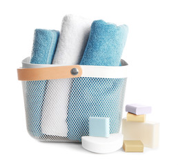 Basket with soft towels and different soap bars on white background