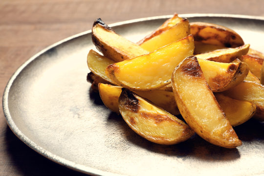 Plate with delicious baked potato wedges, closeup