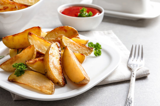 Plate with delicious baked potato wedges on table