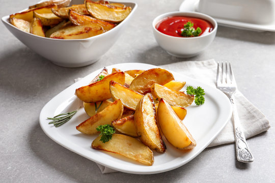 Plate with delicious baked potato wedges on table