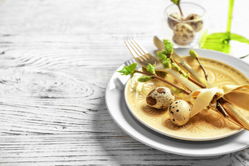 Beautiful festive Easter table setting with quail eggs on wooden background