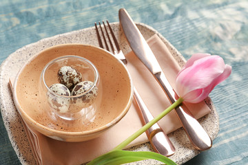 Beautiful festive Easter table setting with quail eggs on wooden background
