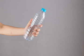 female hand holding a plastic bottle without water.