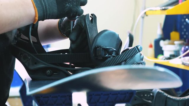 snowboarder fastens the mount to the snowboard. Prepares snowboard for winter to use