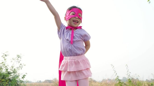Little asian girl in pink superhero costume playing outdoor 