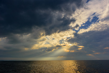 Obraz premium The rays of the sun, making their way through thunderclouds over the ocean