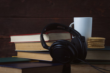 White Cup With Hot Coffee, Cookies and Headphones on Deployed Books on a Dark Wooden Background